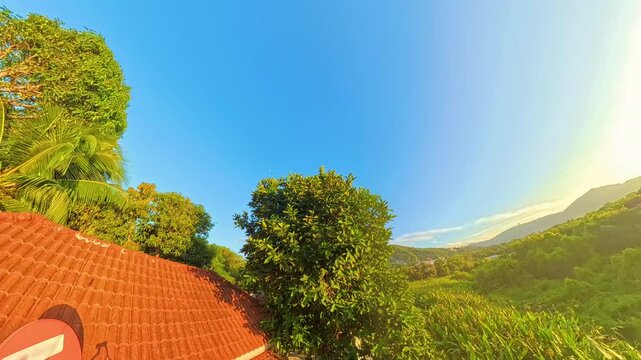 Early Evening Light over Jungle Hills and Rooftops with Clear Blue Sky Timelapse of Sunset in Tropical Forest