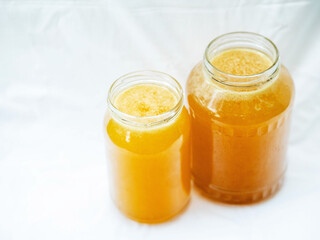 Glass jar of golden bee honey is on a white background. Fine organic product concept. Agriculture and food industry.