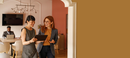 Businesswomen reviewing annual reports on digital tablet while walking and brainstorming new ideas...