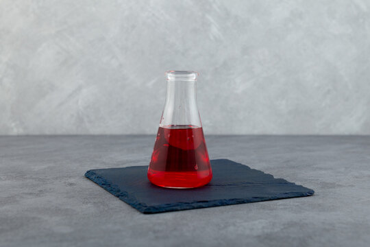 Red liquid in glass lab flask. Powder of azorubine or carmoisine dissolved in water. Red azo dye. Color index of 14720. Food additive E122 also know as Food Red 3 or Azorubin S. Colorant