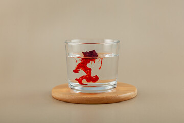 Powder of Allura Red AC or FD&C Red 40 dissolves in water, turning it red. Glass cup with red azo dye. Food additive E129 provides high solubility and stable coloring of products