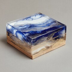 Square, acrylic box with blue and white abstract design, resting on a light wood base