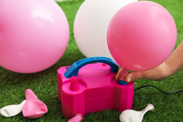 Woman inflating balloon with air pump indoors, closeup