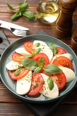 Tasty salad Caprese served on wooden table, above view