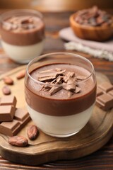 Delicious panna cotta with chocolate and cocoa beans on wooden table, closeup