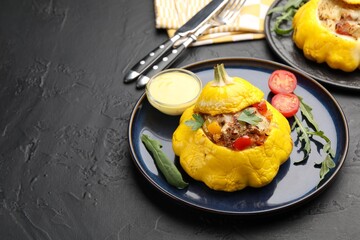 Tasty stuffed pattypan squash with sauce served on black table. Space for text