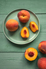 Fresh juicy red peaches on green plates over pastel green background