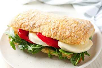 Delicious sandwich with mozzarella cheese, tomato and arugula on table, closeup