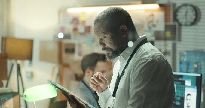 Detective, reading and tablet with man in office for criminal records, arrest warrant and night. Crime investigation deadline, evidence report and digital testimony with person in police department