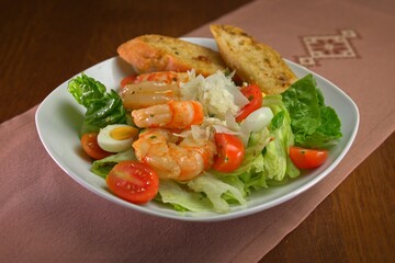 Fresh shrimp salad with lettuce, cherry tomatoes, quail eggs, parmesan shavings, and garlic bread on the side.