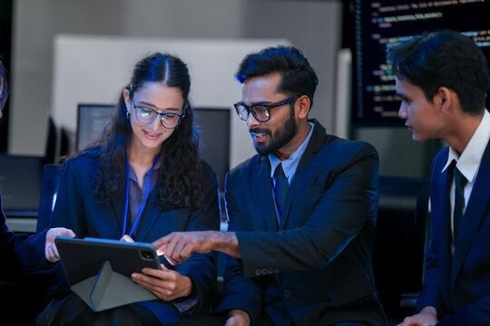 A diverse, multinational team of AI engineers including Indian, East Asian and Caucasian members collaborates on a tablet, developing advanced Generative AI and ethical AGI solutions.