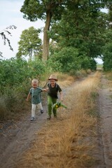 two boys running along a country road holding hands, vacation, rest, village