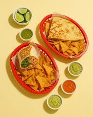 Photo of mexican food burritos and quesadillas with chips and dips on the side