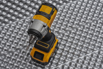 Fototapeta premium Cordless impact wrench rests on a reflective metallic background. Power tools in construction, automotive, or DIY project.