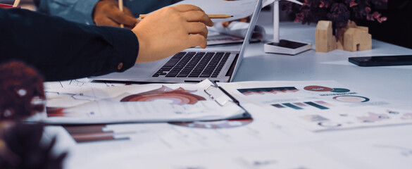 Team members engage in collaborative discussion, analyzing charts and graphs related to sustainability projects, showcasing a modern office with eco-friendly elements and greenery. SACTR