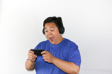 man listening to music with headphones and playing mobile games