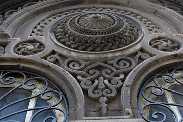 close-up of ornate stone carvings and decorative iron window grilles on a historic building facade.