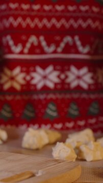 Vertical video. Formed Cookie Dough Balls Lined on Wooden Cutting Board as Woman Shapes Remaining Dough in Festive Kitchen