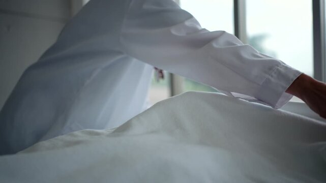 close up side view of dead patient man with cancer in headscarf lying on bed having covering with white sheet by doctor on dead male at hospital ward,
illness and the end of life concept.