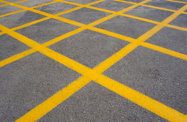 Yellow parking lot lines create a geometric pattern on asphalt surface, showcasing urban design and organization in a public space with copy space