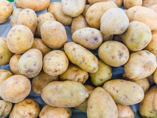 close-up, top-down shot of a large pile of potatoes. The light-colored tubers are a versatile and essential vegetable