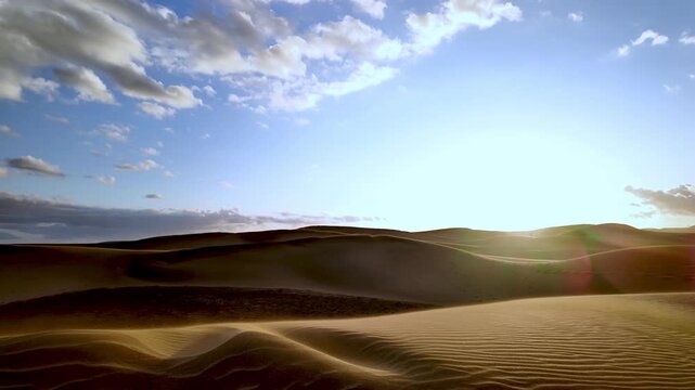 Golden sand dunes landscape changing during sunset with the sun slowly setting behind the horizon, creating a beautiful and peaceful atmosphere