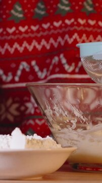 Vertical video. Woman Holding Spoon Over Sifter and Glass Bowl with Dough in Close-Up Vertical Shot during Holiday Baking