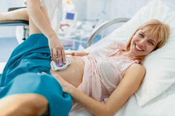 Obraz premium Smiling Pregnant Woman in Hospital Bed During Ultrasound Examination in Bright Modern Hospital Room