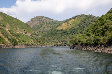 Fototapeta premium Boat tour through the Sil Canyon in Ribeira Sacra, Galicia, Spain, departing from Embarcadoiro da Ponte do Sil, Monforte de Lemos. Scenic river and vineyards.
