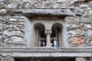 Fototapeta premium Ancient Stone Window with Column in Rough Stone Wall of Old Building 