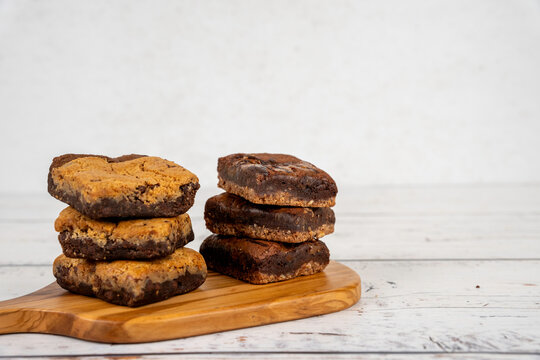 Stacks of brookie and caramel swirl brownies on a wood cutting board