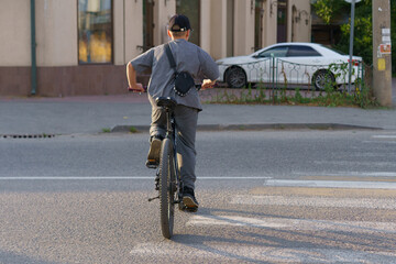 Fototapeta premium Young boy riding bicycle down the street on a sunny day in an urban setting