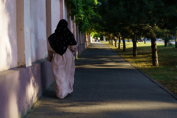 Woman walking along a tree-lined path in the evening light