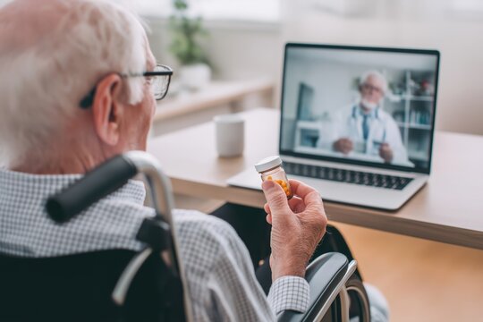 Senior man in a wheelchair discusses his prescription via telehealth with a doctor - Powered by Adobe