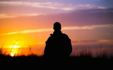 Silhouette of person watching stunning sunset over field, creating a peaceful and contemplative atmosphere, perfect for travel content