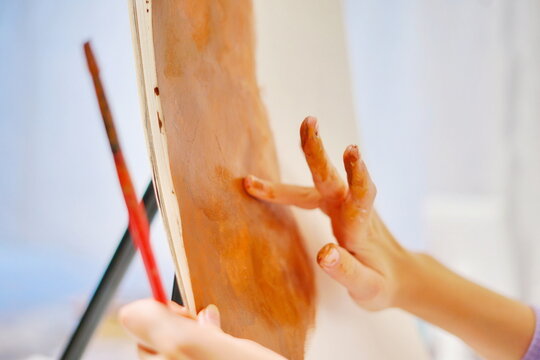 Close-up of a girl adjusting paint with her fingers in a sketchbook