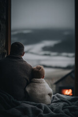 father and son enjoy quiet moment together as snow softly falls outside their window