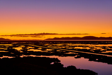 First light breaks over Lake Titicaca, painting the waters and Andes in hues of gold and rose — a...