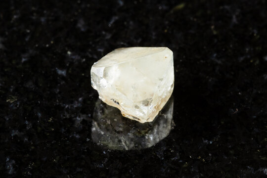 sample of rough topaz crystal on black granite