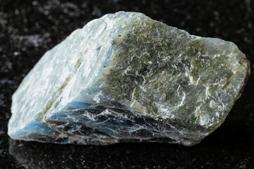 sample of rough labradorite rock on black granite