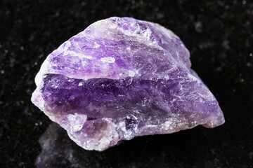 Fototapeta premium sample of raw amethyst rock on black granite