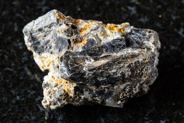Fototapeta premium sample of raw anthraconite rock on black granite