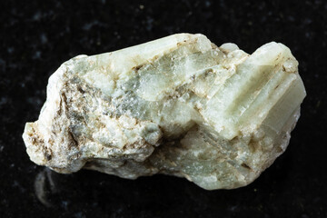 sample of raw beryl rock on black granite