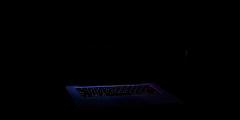 Silhouette of firearm above laptop on dark background, violence, hidden