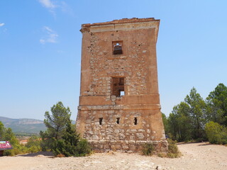 Requena,19th century telegraph tower in Mediterranean countryside, historic communication building under bright blue sky 