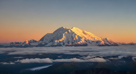 The majestic snow-covered peak of Denali in Alaska is bathed in golden sunlight rising spectacularly above a sea of clouds at dawn or dusk.