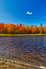 Light waves hug the shore of the lake with a beautiful cloud floating above the horizon in the fall.