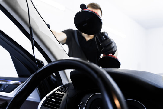 Windshield replacement using lifting tools that grip glass securely. Windshield technicians rely on vacuum lifters for glass removal. Windshield removal and installation using suction lifters.