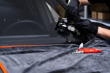 Windshield crack repair using resin injection. Technician using windshield injector tool to fix bullseye crack. Resin repair on windshield using injector application to restore structural clarity.