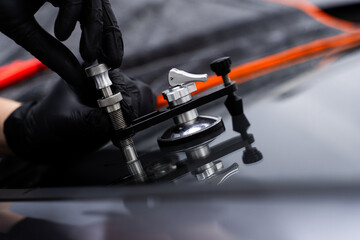 Windshield crack repair using resin injection. Technician using windshield injector tool to fix...